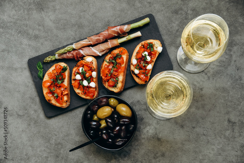 Snacks in the restaurant bruschetta with tomatoes and asparagus with prosciutto and olives two glasses of white wine or prosecco