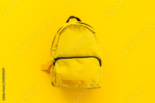 Classic yellow school backpack top view. Educational objects background