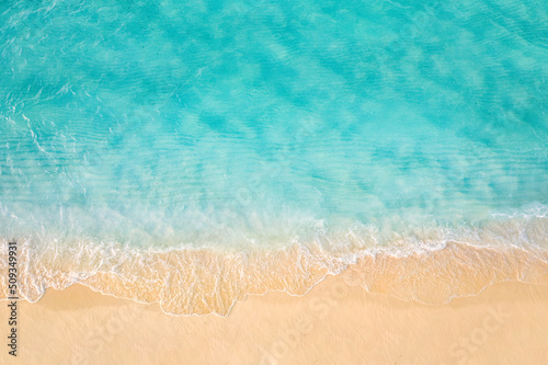 Sandy seashore with turquoise green sea water. Small waves on the beach. Beautiful paradise tropical island beach background, top aerial landscape turquoise ocean on sunny day. Freedom summer travel