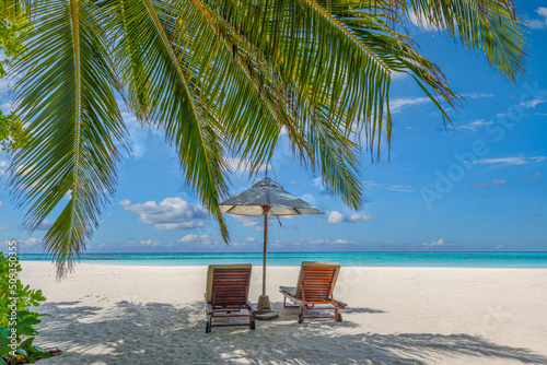 Beautiful tropical island, two chairs, umbrella under palm tree leaves, paradise sea sand sky. Summer travel landscape, vacation beach scenic, idyllic exotic nature closeup of recreation, relaxation. 