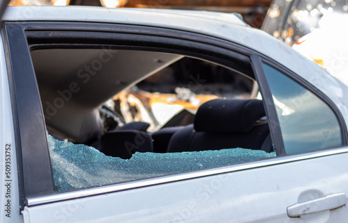 Criminal incident. Breaking into a car parked on the street. Broken side glass and the passenger compartment behind it. A crime committed by a thief, stealing things. Car after an accident.