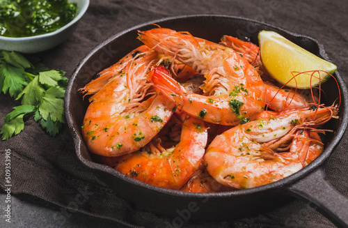 Shrimps in pan stir-fried tasty jumbo shrimps in pan on dark background close up. 