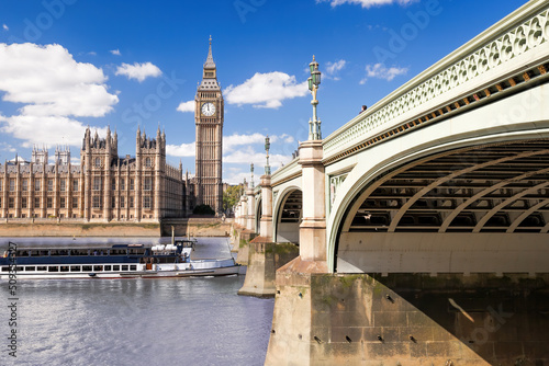 Famous Big Ben with bridge over Thames and tourboat on the river in London, England, UK photo