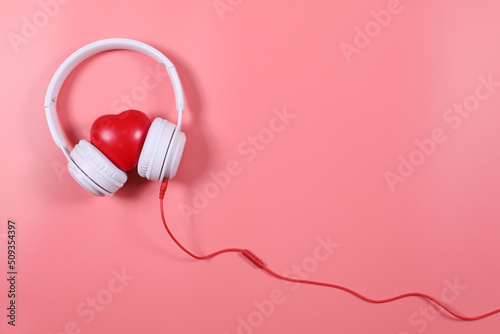 White headphone with red heart isolated on pink background, flat lay photography have copy space.