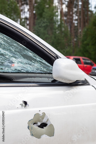 Car riddled with bullets. War of Russia against Ukraine. A car of civilians shot by the Russian military during the evacuation of women and children. Traces of bullets and fragments of shells. photo