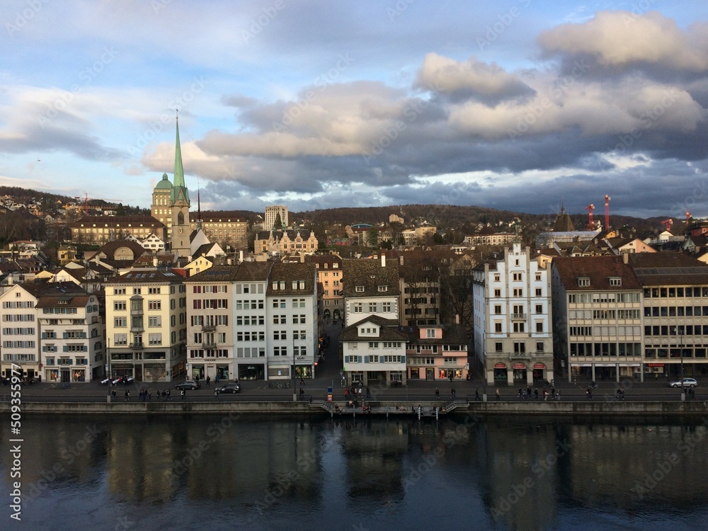 View from the highest point of the old town in Zürich over the Limmat River until the Zürichberg. Buildings are reflected in the water and the ETH and Polyterrase also appear.