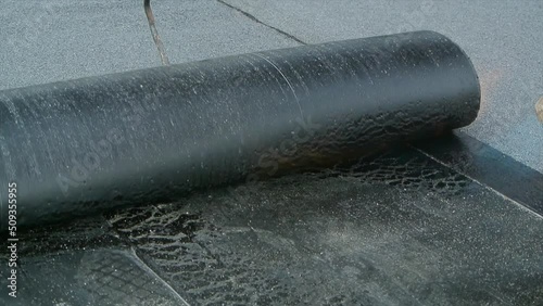 Roofer team lay black roofing material on flat roof