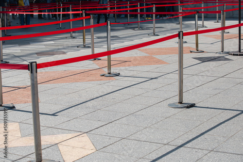 Temporary fencing to organize the direction of the flow of people - metal posts and red tape - queuing for the public