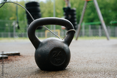 Fototapeta Naklejka Na Ścianę i Meble -  Close-up of kettlebell on an outdoor sports field. Selective focus on sports equipment for weightlifting