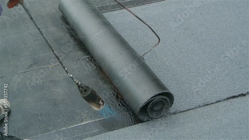 Roofer team lay black roofing material on flat roof