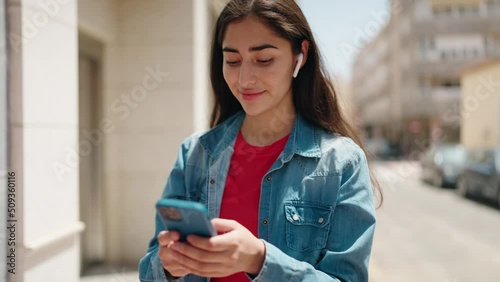Young hispanic girl smiling confident listening to music and dancing at street