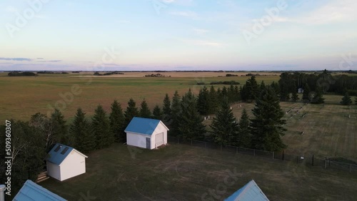 Beautiful white and blue country church next to a small cemetery and two huts at sunset in Alberta, Canada. Wide angle revealing pull back shot photo