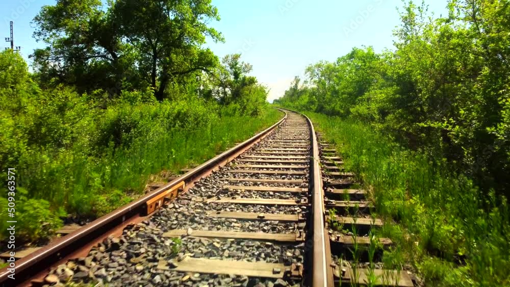 Old rusty rails of an abandoned railway. A sunny June day. The sun is already at sunset, long shadows. High embankment, sparse trees on the roadsides. Old rusty rails of an abandoned railway. A sunny June day. The sun is already at sunset, long shadows. High embankment, sparse trees on the roadsides.