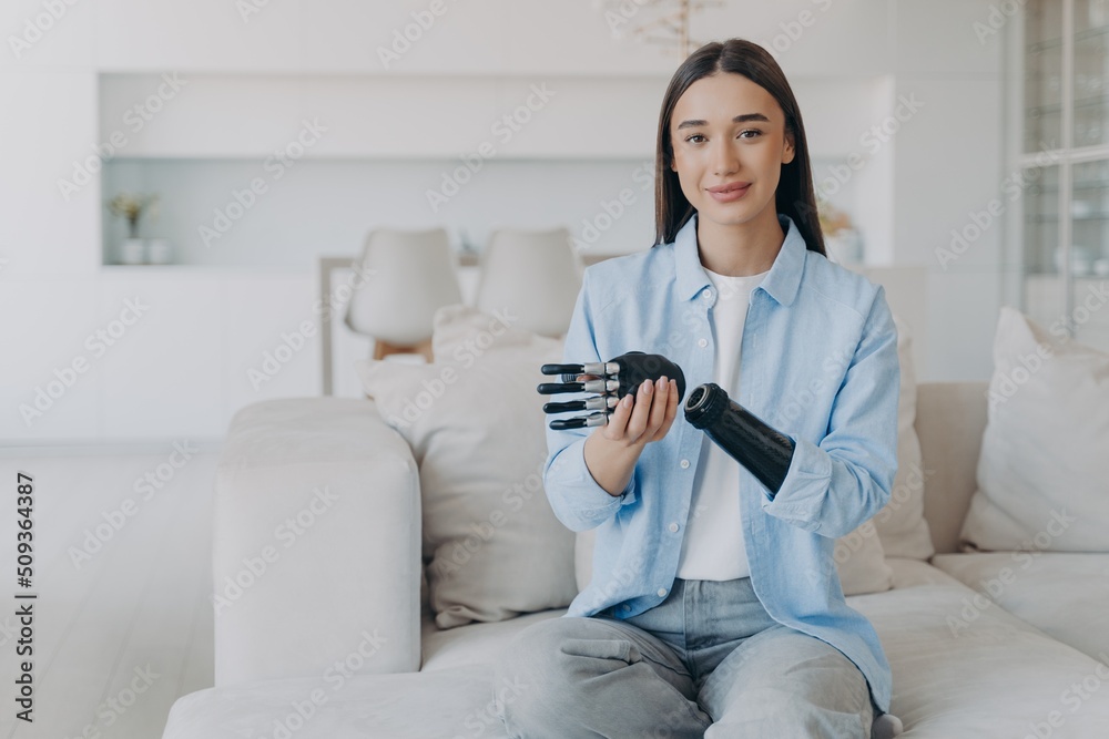 Positive disabled young woman is disassembling bionic arm prosthesis and smiling. Positive disabled young woman is disassembling bionic arm prosthesis and smiling.