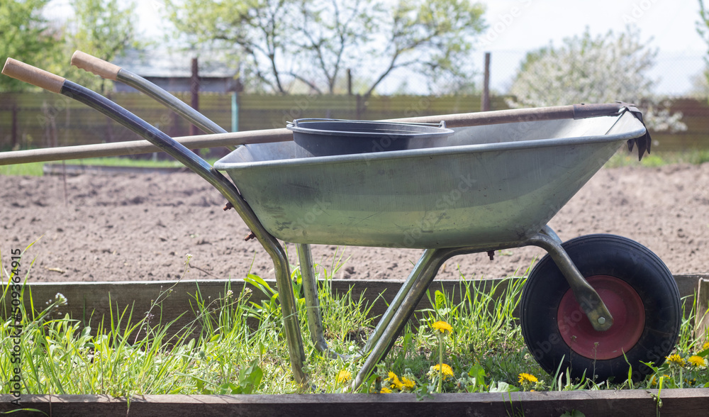Gray metal garden wheelbarrow with two handles and one wheel. The ...