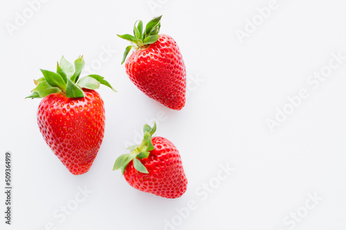 Top view of ripe strawberries with leaves on white background.