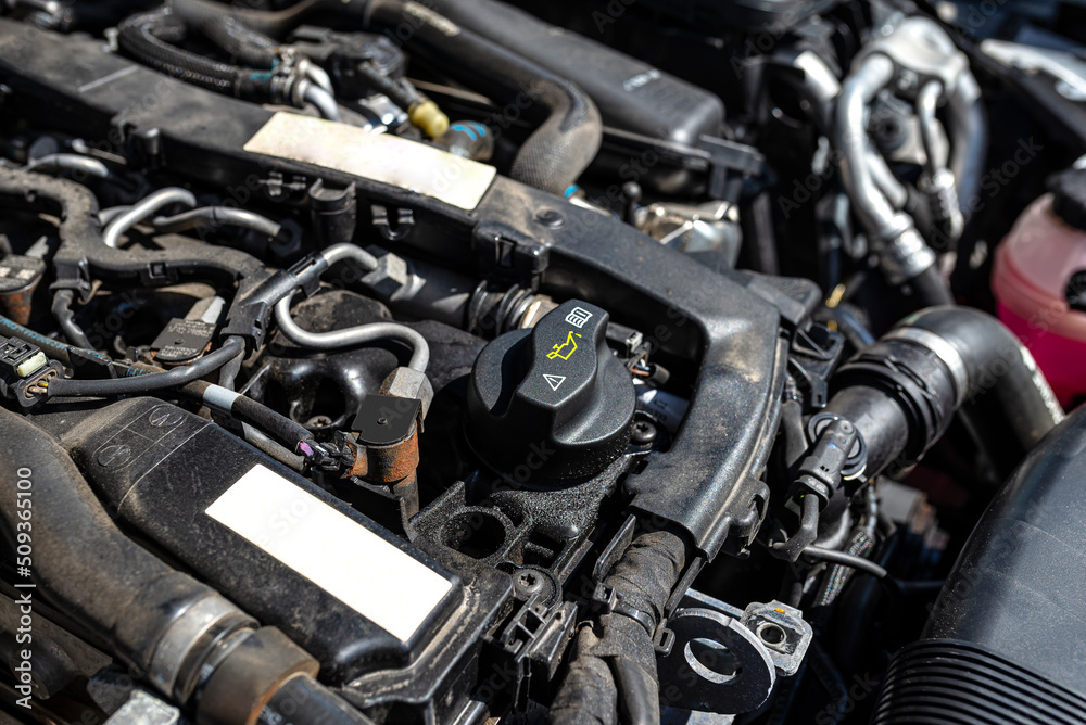 Engine compartment in a diesel car, visible closed oil filler in black and engine parts. Engine compartment in a diesel car, visible closed oil filler in black and engine parts.