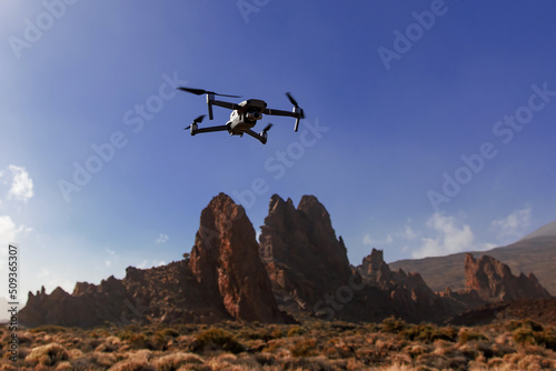 Folding small drone is flying over the mountains.