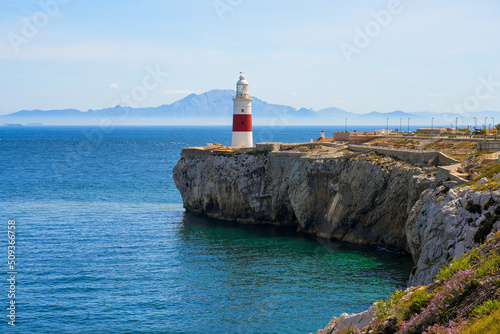 Europa Point Lighthouse facing the strait of Gibraltar on top of sea cliffs with the mountains of Morocco on the distance photo