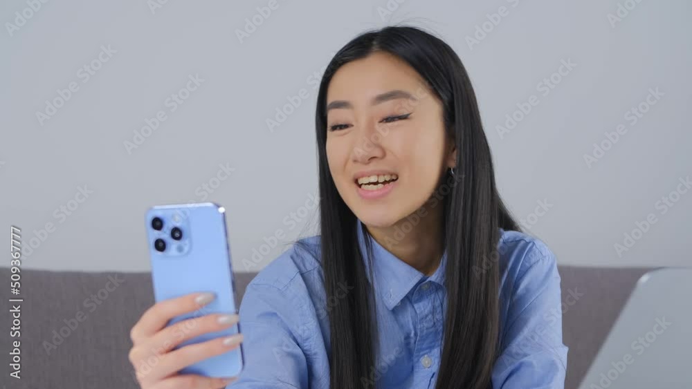 Happy asian girl speaking on frontal camera during video call. Cheerful Vietnamese female person calling friends online with smartphone. BIPOC person lifestyle video clip