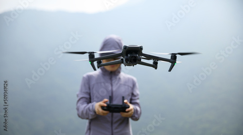 Woman remotel control a flying drone in spring forest photo