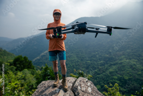 Woman remotel control a flying drone in spring forest photo