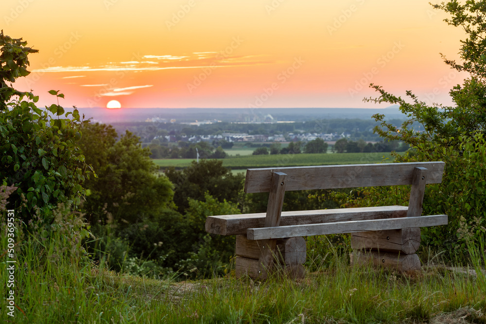 A beautiful sunset late Spring over the rolling hills from south Limburg. The wooden bench is an idyllic place for couples to enjoy a romantic evening overlooking to landscape. A beautiful sunset late Spring over the rolling hills from south Limburg. The wooden bench is an idyllic place for couples to enjoy a romantic evening overlooking to landscape.