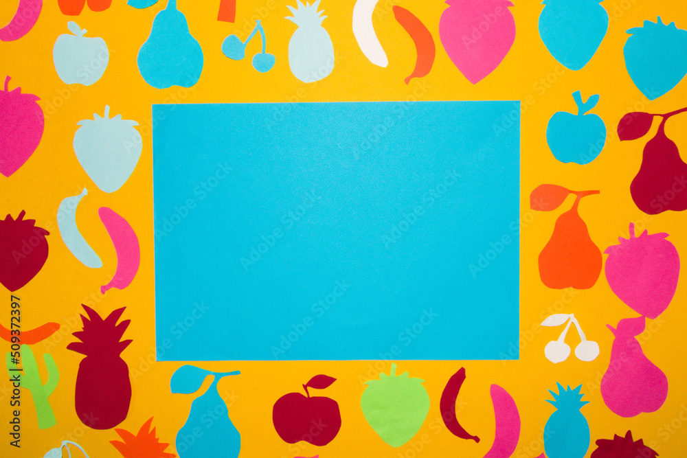 blue blank paper for copy space, surrounded by orange background with colorful paper fruit, creative concept, vitamins