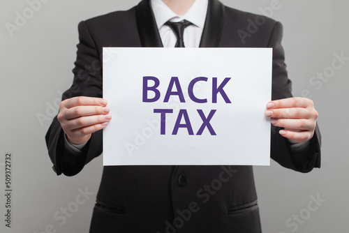 Businessman showing white paper banner with back tax inscription close up