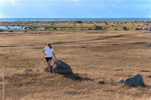 The landscape at the southern tip of the Swedish island of Öland in the Baltic Sea. Young man looks over the grandiose landscape with countless stone blocks.