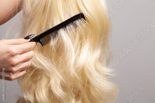 Blonde hair and black plastic comb in barber hands