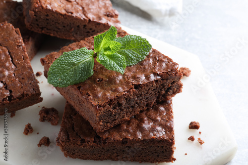 Delicious chocolate brownies with fresh mint on table, closeup