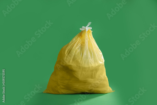 Trash bag full of garbage on green background