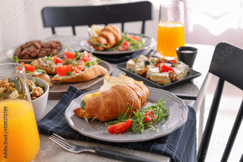 Tasty croissant sandwich and many different dishes served on buffet table for brunch