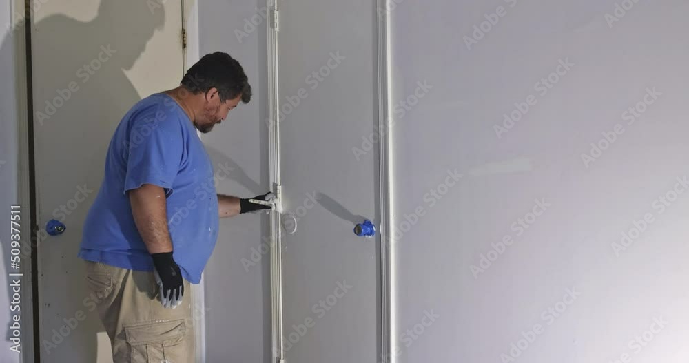 Painting trim molding of wooden door, workers using paint brush Painting trim molding of wooden door, workers using paint brush