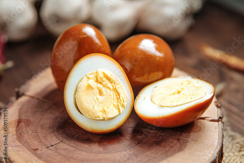 Brown marinated pickled egg slices on wooden board photo