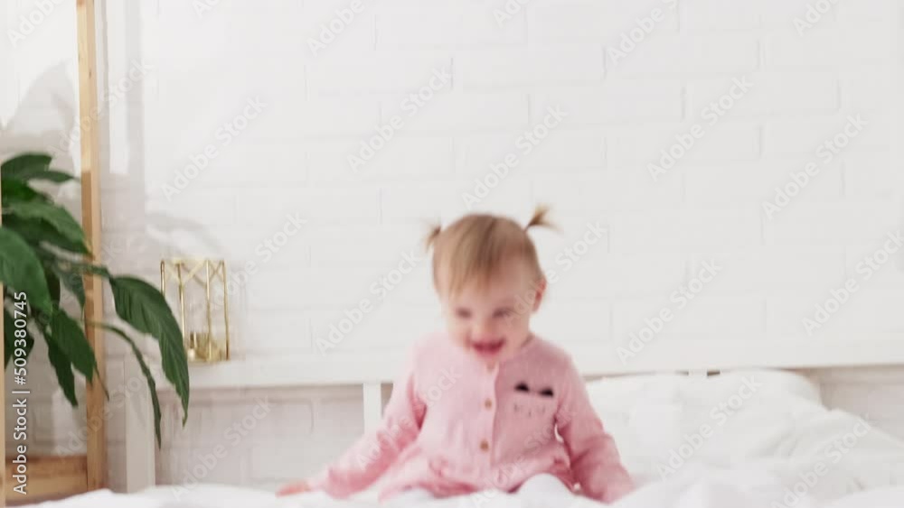 Happy child girl having fun jumping and playing funny active game in parents bed, Bouncing, fooling around, frolics , laughing at home