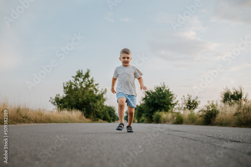 Little boy is running on road in summer