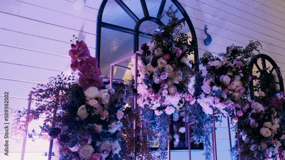 in the dark hall there are festive tables and chairs, tables decorated with compositions of flowers, greenery and candles. On the tables are glasses, plates and cutlery