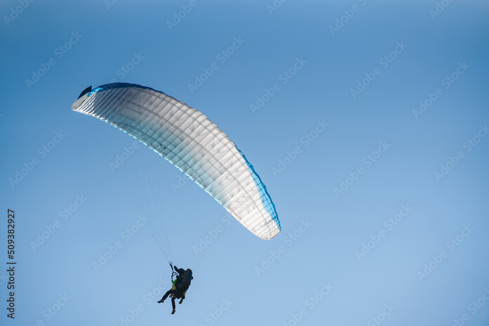 Paraglider in the blue sky. The sportsman flying on a paraglider. Paraglider in the blue sky. The sportsman flying on a paraglider.