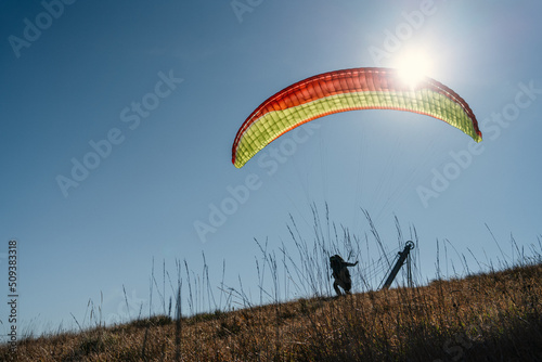 Paraglider landing on the ground against the blue sky.
