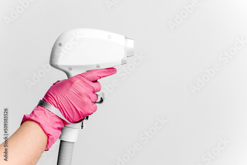 A woman tunes a laser hair removal machine. She holds a working part of the epilator in her hands and poses for a photo. Body Care. Underarm Laser Hair Removal. photo