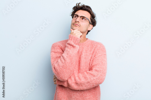 young handsome man feeling thoughtful, wondering or imagining ideas, daydreaming and looking up to copy space photo