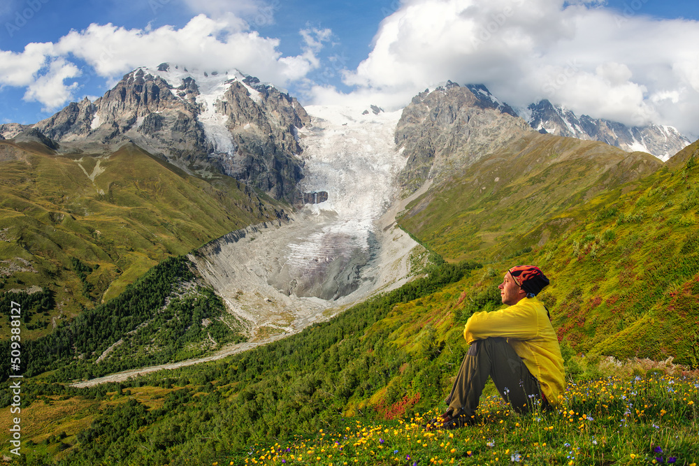 A man in a yellow jacket looks at the Adishi Lardaad glacier in Georgia. Svaneti.