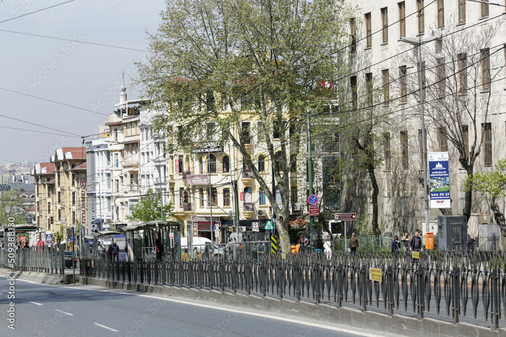 Istanbul, Turkey - April 2022: Street with a road, tram stop and a lot of people with the buildings with European facades