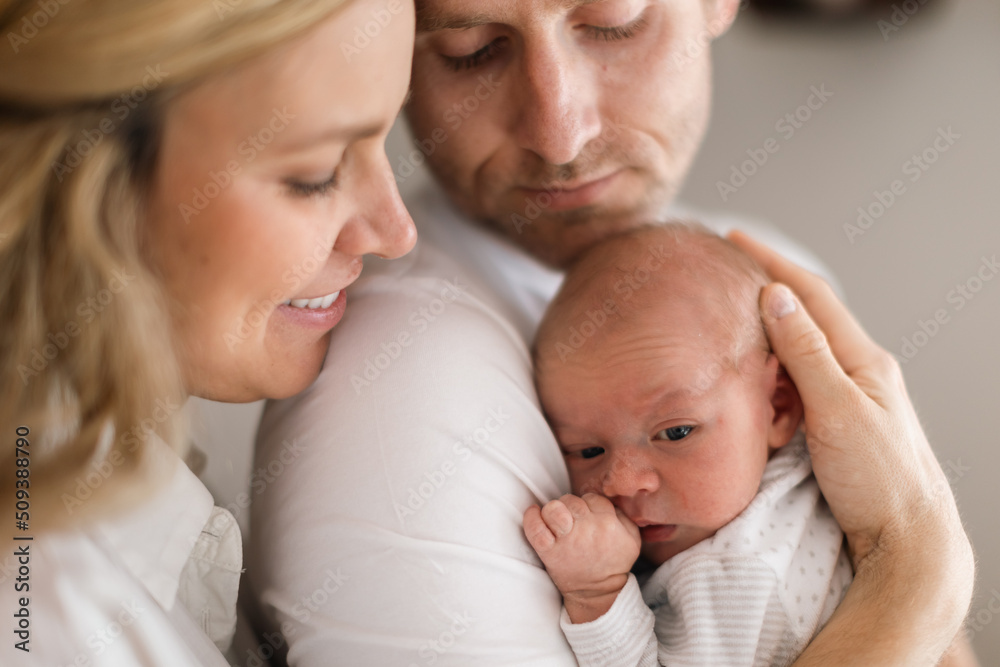 Smiling mother and father holding their newborn baby daughter at home Smiling mother and father holding their newborn baby daughter at home