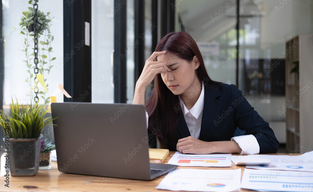 Image of an Asian business woman is stressed, bored, and overthinking from working on a tablet at the office. Image of an Asian business woman is stressed, bored, and overthinking from working on a tablet at the office.