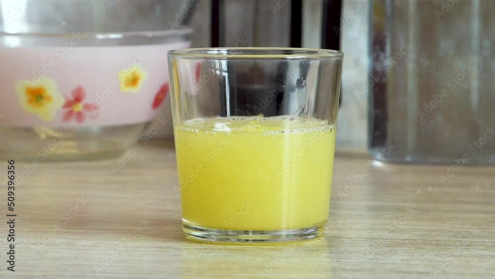 Lemon juice is poured into a glass. Yellow fruit. Vitamin C. Juicing. tropical fruit. Diet. Close-up. Kitchen in the house. Refreshing drink. Lemon juice is poured into a glass. Yellow fruit. Vitamin C. Juicing. tropical fruit. Diet. Close-up. Kitchen in the house. Refreshing drink.