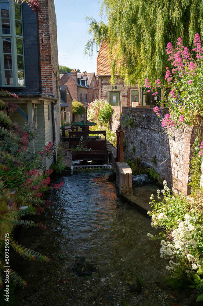 Small river flows throughout beautiful French village Veules-les-Roses, old houses and flowers