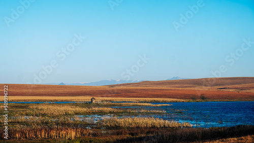 Fishing hut next to a lake in the countryside. Mountains in the background
